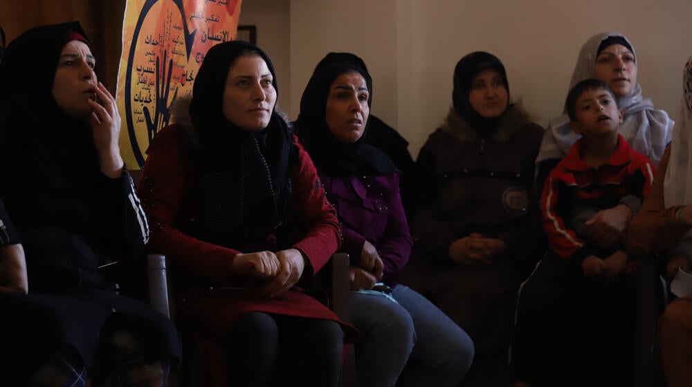 Un groupe de femmes et un jeune garçon sont assis à l’intérieur du centre Al-Husseiniyah du village d’Ashrafieha, dans une zone rurale de Homs.