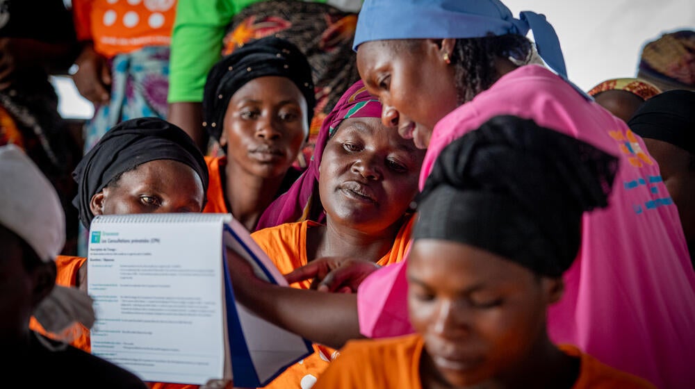 A midwife and multiple women are in a mobile clinic where an information session is held for pregnant women.