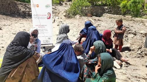 Un grupo de mujeres y niños conversan en el exterior sobre un suelo rocoso